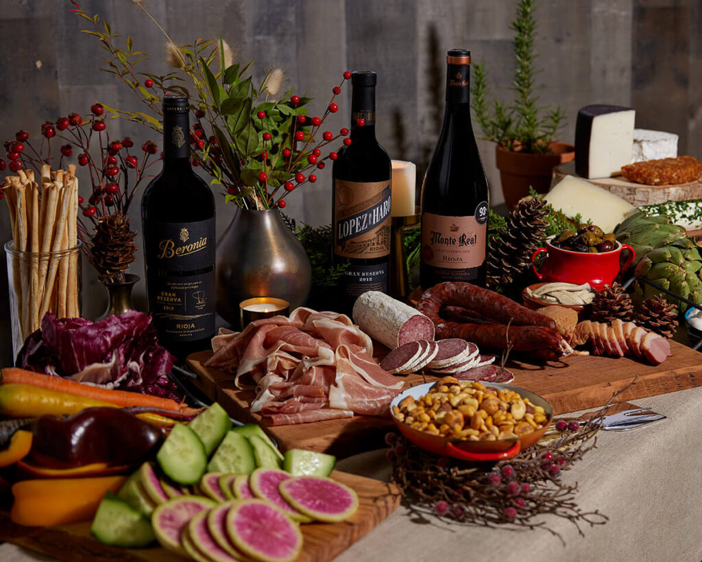 charcuterie board with meats, cheeses, nuts and bottle of Rioja wine