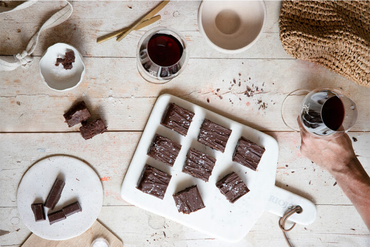 a board of chocolates with two glasses of red wine
