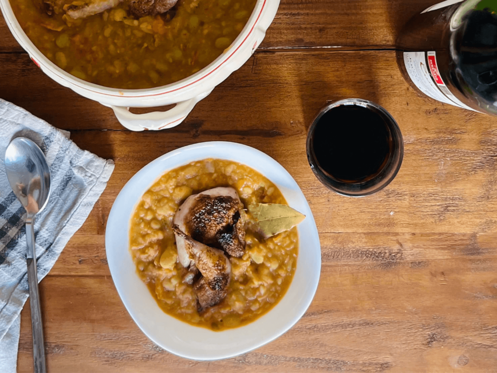 Bowl of white beans and quail with a glass of Rioja