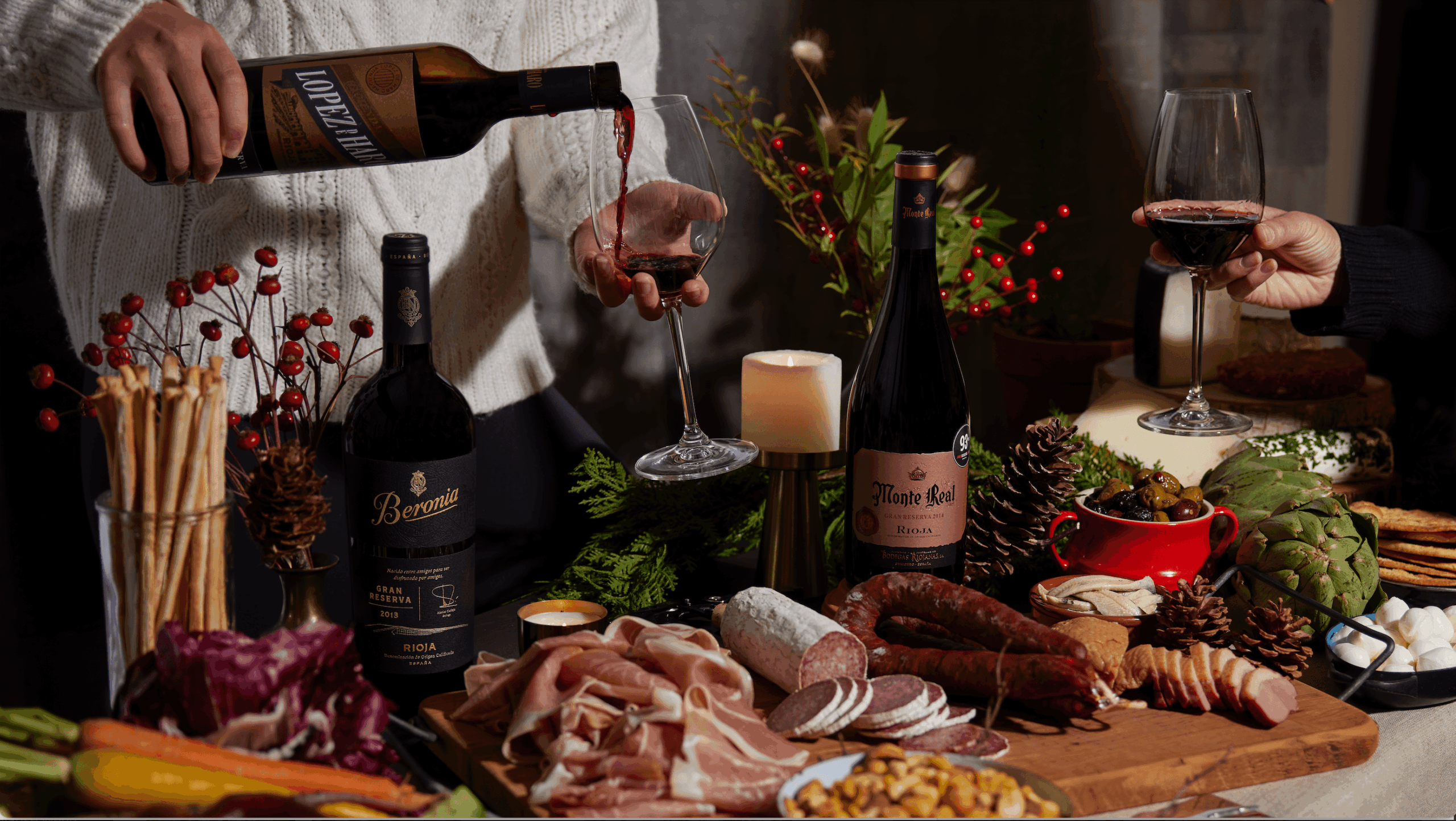 Pouring red wine at a table set with a charcuterie board